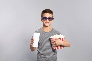 3d gözlük, patlamış mısır ve içecek gri arka plan üzerinde sinema gösterisi sırasında bir çocuk