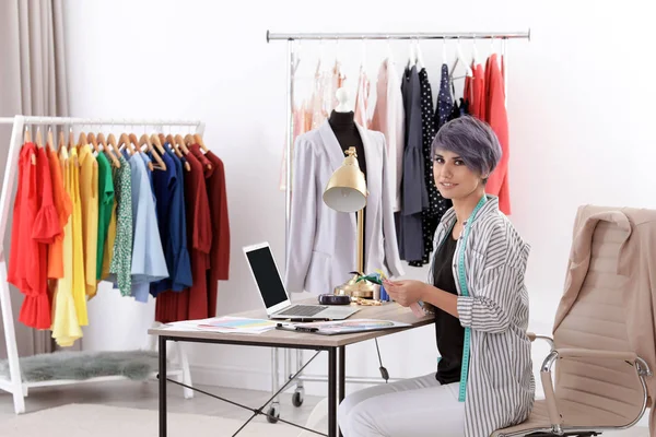 Güzel genç stilist Studio dizüstü bilgisayar ile çalışma. Moda giysiler