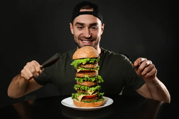 Young Man Cutlery Eating Huge Burger Black Background — Stock Photo, Image