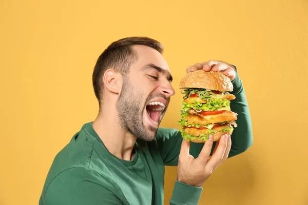 Jovem Faminto Comendo Hambúrguer Enorme Fundo Cor — Fotografia de Stock