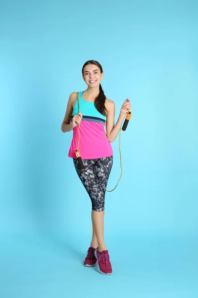 色の背景上のジャンプ ロープを持つ若い陽気な女性の完全な長さの肖像画 — ストック写真