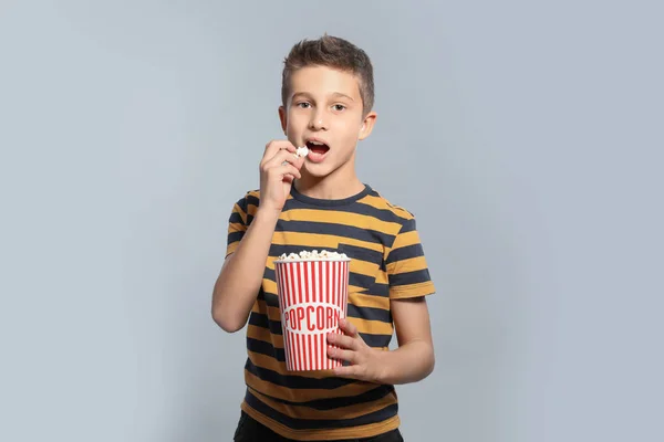 Boy with popcorn during cinema show on grey background