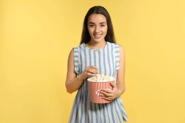 Woman with popcorn during cinema show on color background