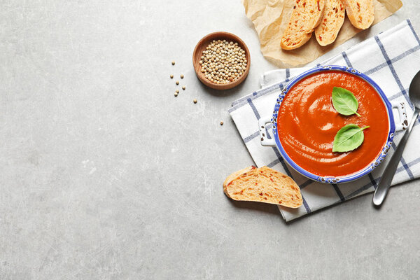 Fresh homemade tomato soup served with bread on grey table, top view. Space for text