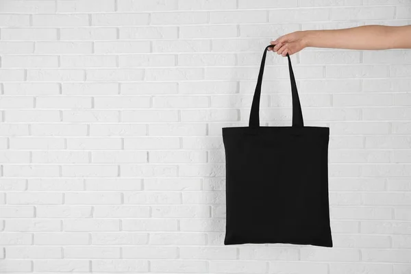 レンガの壁の近くに Eco バッグを保持している女性 デザインのために模擬します — ストック写真