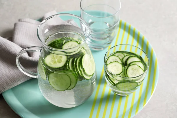 Glasses and jug of fresh cucumber water on tray