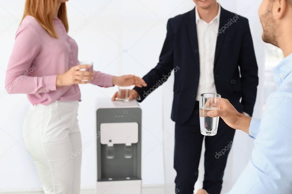 Co-workers having break near water cooler on white background, closeup