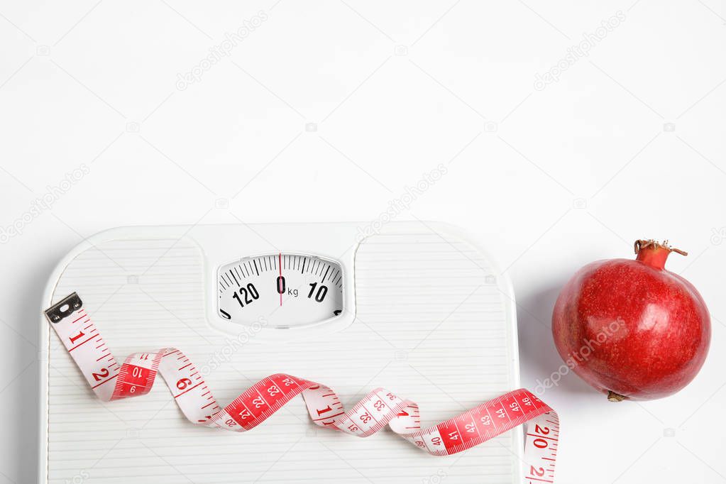 Composition with scales, tape measure and pomegranate on white background, top view