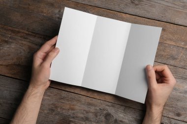 Boş broşür görünümünün üzerinde ahşap arka plan üzerinde olan adam. Tasarım için alay