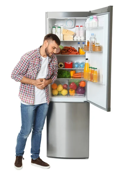 Молодой Человек Чувствует Себя Больным Возле Открытого Холодильника Белом Фоне — стоковое фото