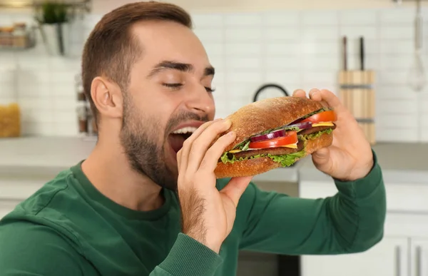 Genç Adam Mutfakta Lezzetli Sandviç Yeme — Stok fotoğraf