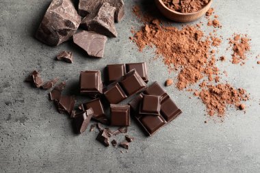 Adet çikolata ve kakao tozu, düz gri arka plan üzerinde yatıyordu