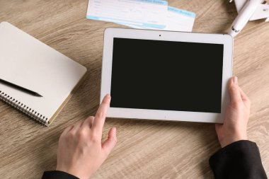 Tablet boş ekran ile masa üzerinde closeup tutan kadın. Seyahat acentası