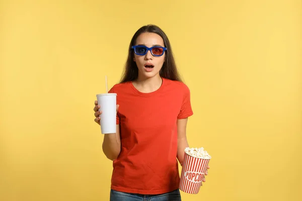 Woman with popcorn during cinema show on color background