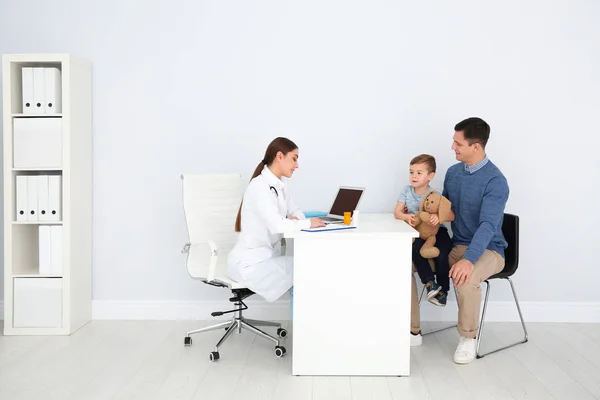 Father and son visiting pediatrician. Doctor working with patient in hospital