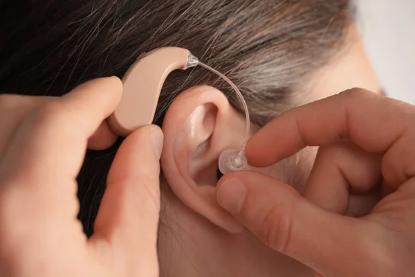 Doctor putting hearing aid in patient\'s ear, closeup