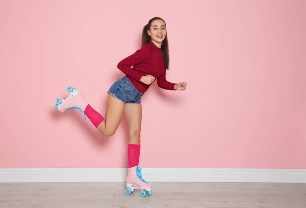 Full length portrait of young woman with roller skates on color background