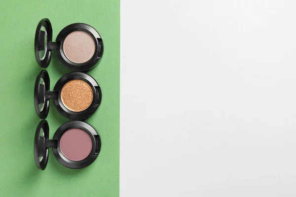 Flat lay composition with different eye shadows on color background. Space for text