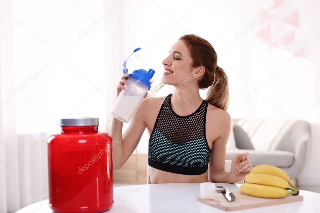 Young sporty woman with bottle of protein shake at home
