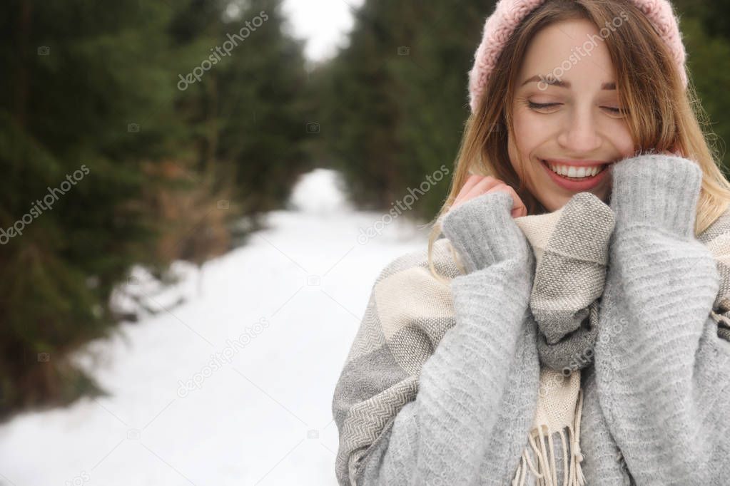 Young woman in snowy conifer forest, space for text. Winter vacation