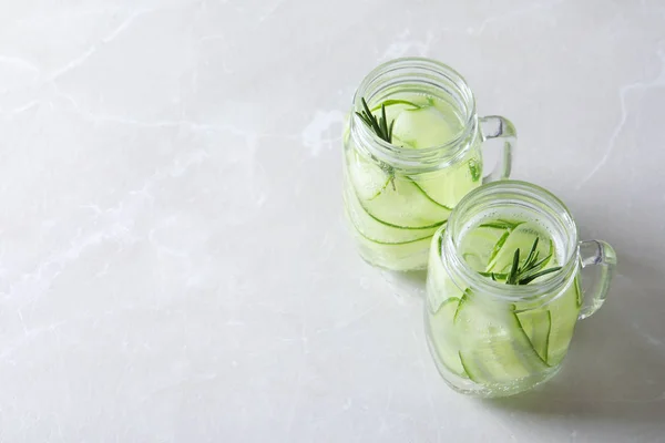 Mason jars of fresh cucumber water on grey background. Space for text