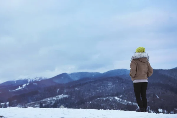 Woman in warm clothes enjoying mountain landscape, space for text. Winter vacation