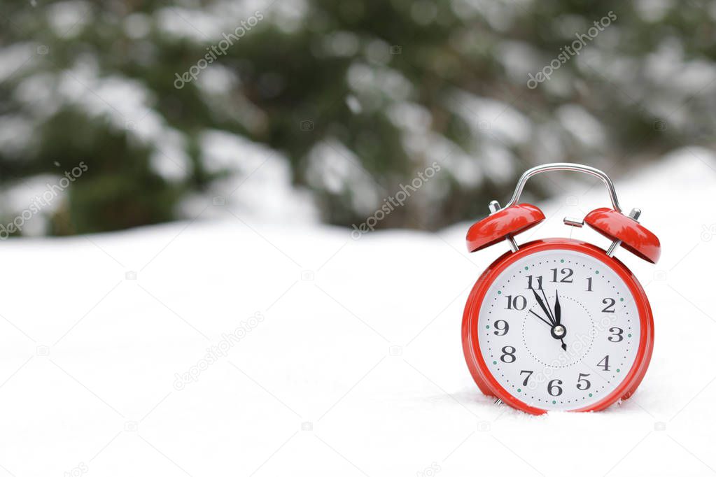 Red alarm clock on white snow outdoors. Space for text