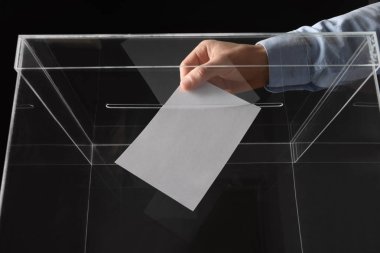 Adam onun oy oy sandığı siyah arka plan üzerine, closeup koyarak.