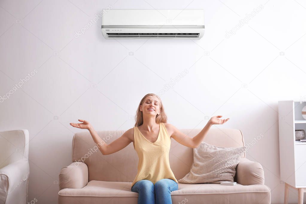 Young woman relaxing near air conditioner at home