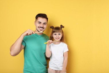 Küçük kız ve babası birlikte renk arka plan, metin için yer üzerinde diş fırçalama