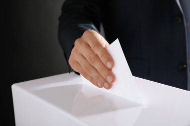 Adam onun oy oy sandığı siyah arka plan üzerine, closeup koyarak.