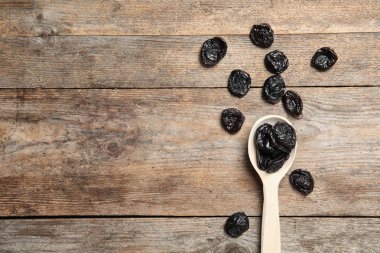 Kaşık ahşap arka plan, metin için yer ile üstten görünüm üzerinde kurutulmuş erik. Sağlıklı meyve