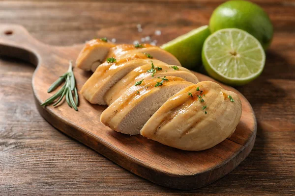 Holzbrett Mit Gebratener Hühnerbrust Und Limetten Auf Dem Tisch Nahaufnahme — Stockfoto