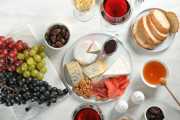 Wine and snacks served for dinner on light table, flat lay