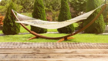 Wooden table and blurred view of garden with hammock on background. Space for text