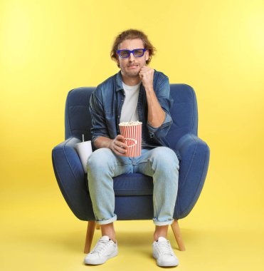 3d gözlük, patlamış mısır ve renk arka plan üzerinde sinema gösterisi sırasında koltukta oturan içecek ile duygusal adam