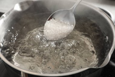 Ocakta, closeup tencerede kaynar su tuzlama