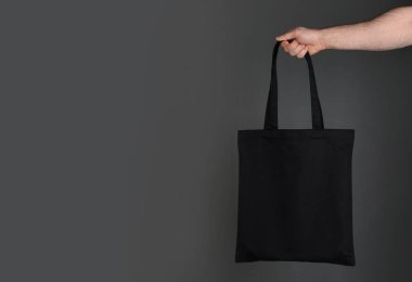 Holding adam alışveriş Eko çanta gri arka plan üzerinde pamuk. Mockup tasarım için
