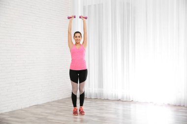 Evde, egzersiz yaparak dumbbells ile genç güzel kadın metin için yer. Egzersiz ve fitness