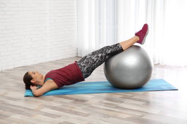 Evde egzersiz yaparak topu ile genç güzel kadın. Egzersiz ve fitness