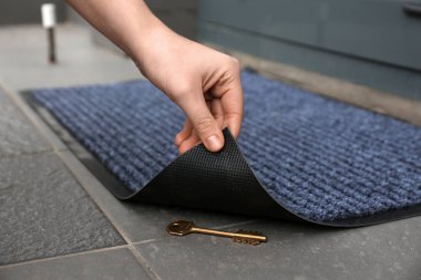 Kadın eli anahtar altında gizli portre ortaya çıkarmak için kapı altlığı kaldırma