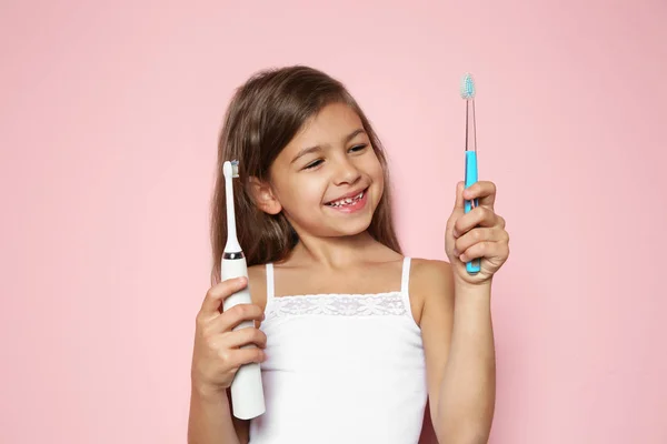 Menina Escolhendo Entre Escovas Dentes Manuais Elétricas Fundo Cor — Fotografia de Stock