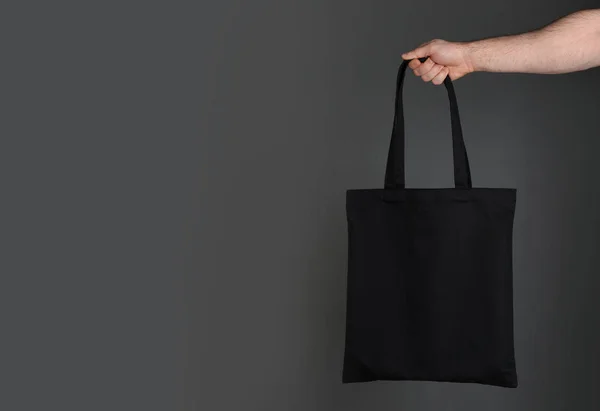 男子拿着棉购物袋在灰色的背景 用于设计的模型 — 图库照片