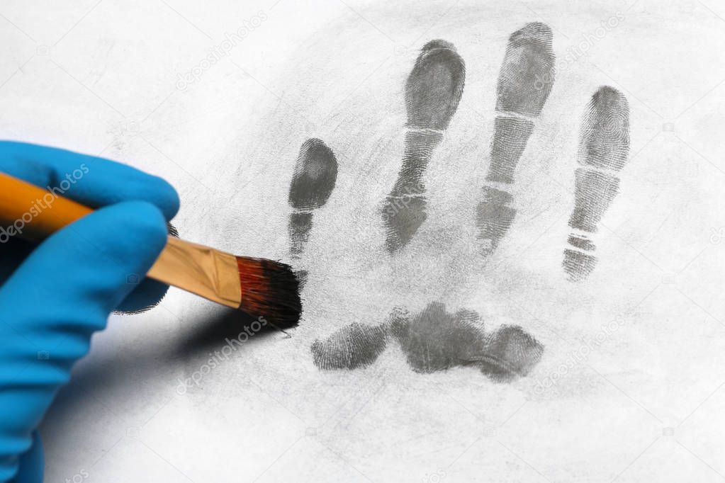 Criminalist taking fingerprints with brush from light surface, closeup. Forensic investigation