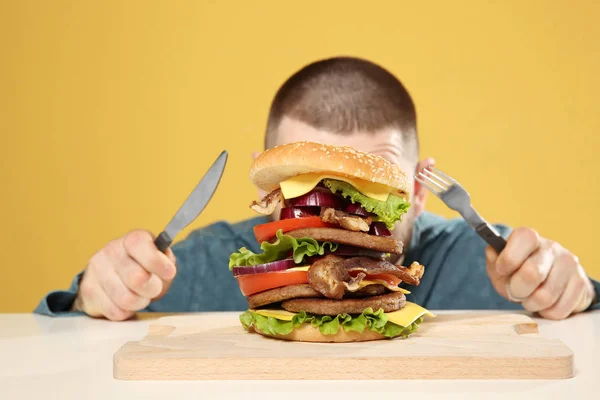 Joven Con Cubiertos Sabrosa Hamburguesa Enorme Mesa —  Fotos de Stock