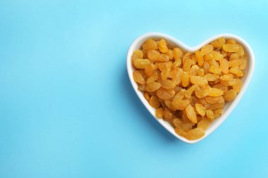 Renk arka plan üzerinde kuru üzüm, metin için yer ile üstten görünüm kase. Kurutulmuş meyve sağlıklı çerez olarak