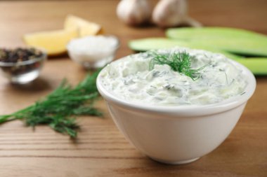 Cucumber sauce with ingredients on wooden background, space for text. Traditional Tzatziki clipart