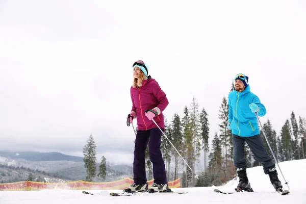 Joyeux Couple Avec Équipement Ski Assis Sur Une Colline Enneigée — Photo