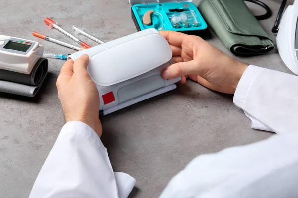 Doctor with digital pressure meter and different medical objects at table, closeup