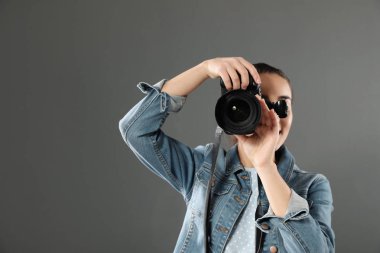 Genç kadın ile fotoğraf makinesi gri bir arka plana dayanır. Profesyonel fotoğraf stüdyosu